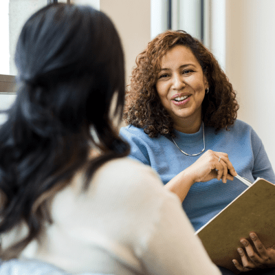 two people stand over a desk shaking hands