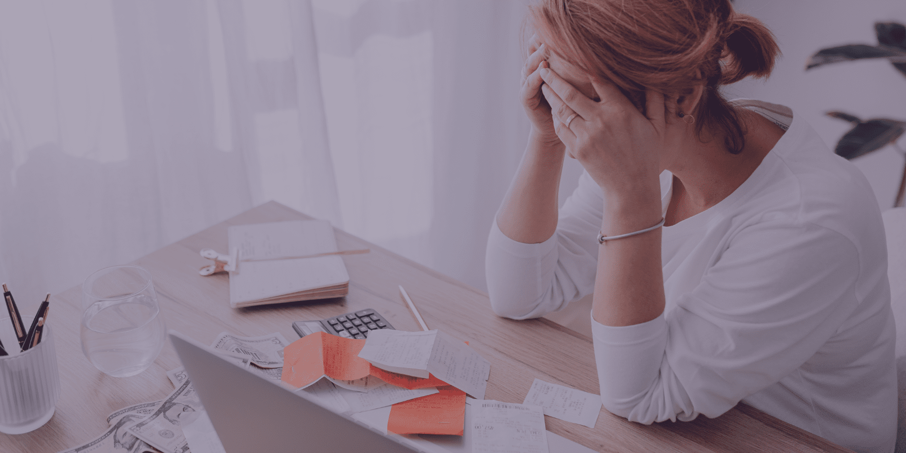 recover unpaid invoices - person sits at a desk looking at receipts and calculator, head in hands