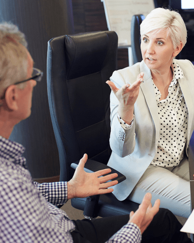 two people stand over a desk shaking hands